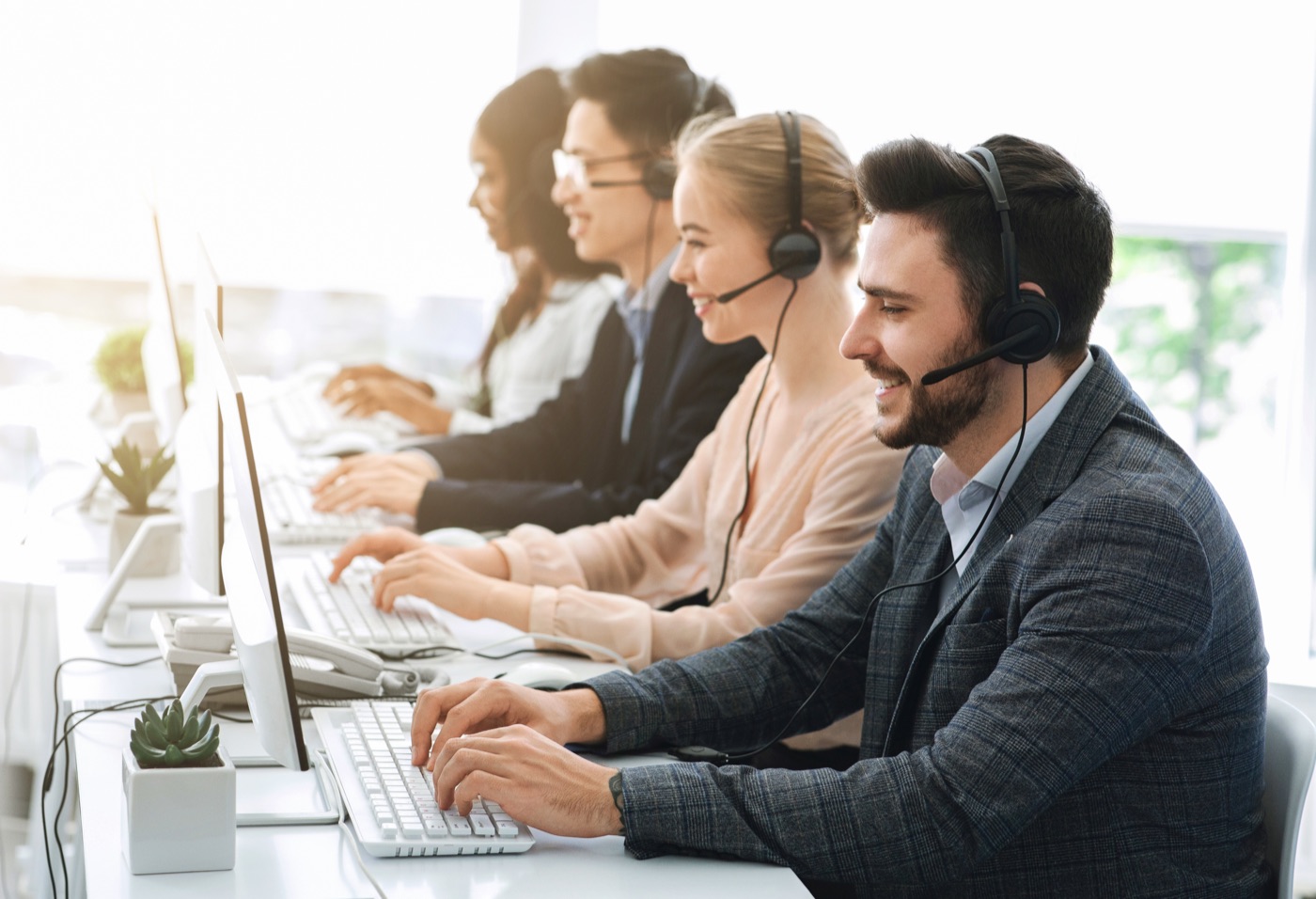 Mitarbeiterinnen und Mitarbeiter mit Headsets im Büro