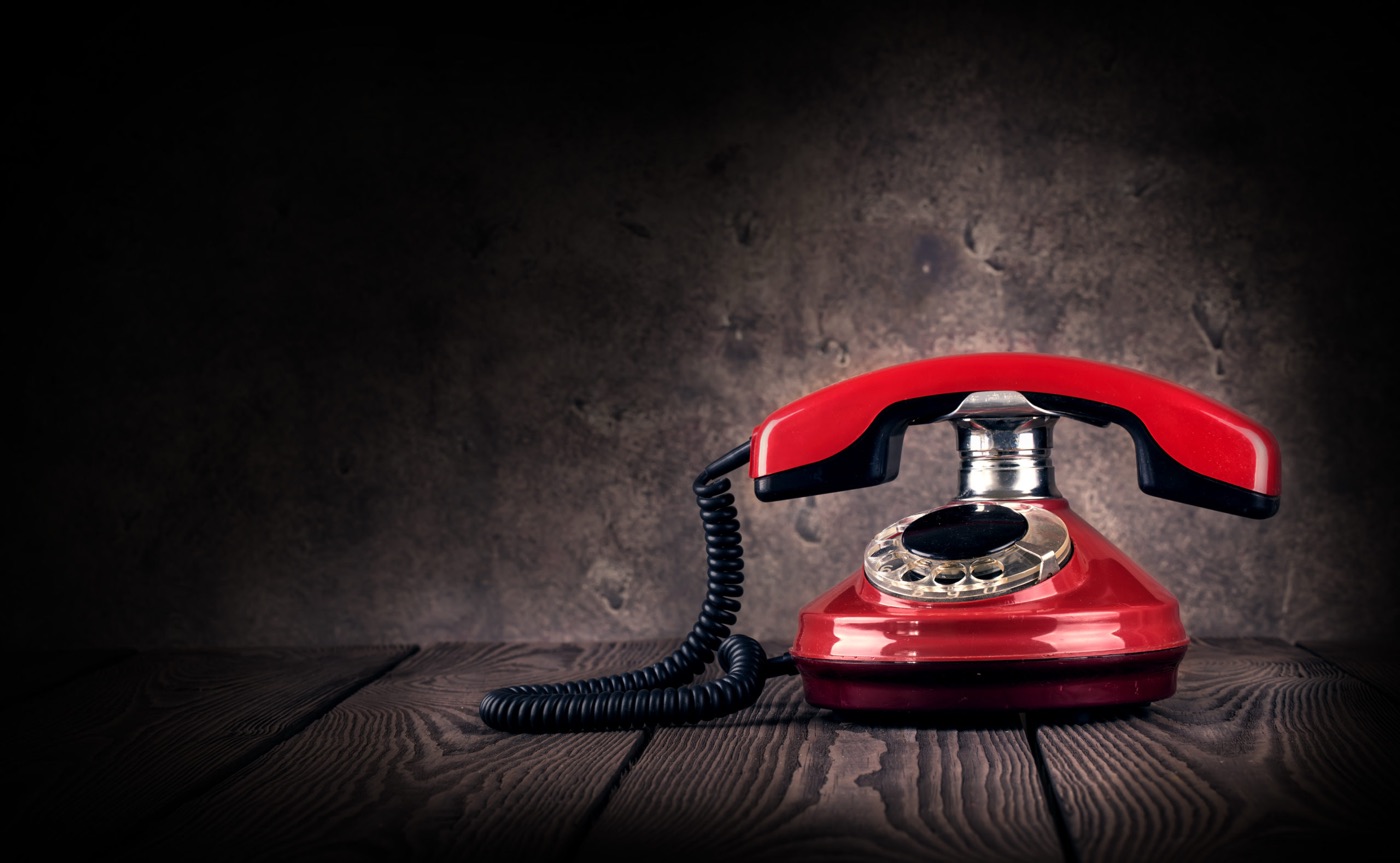 Rotes Telefon mit Wählscheibe auf einem Holztisch